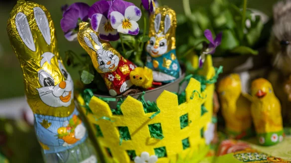 Osterhasen und K&uuml;ken aus Schokolade stehen zwischen bl&uuml;henden Stiefm&uuml;tterchen. Die Osterklassiker werden teurer: Die Menschen in NRW m&uuml;ssen f&uuml;r das Osterfest 2025 tiefer in die Tasche greifen. - &copy; picture alliance/dpa