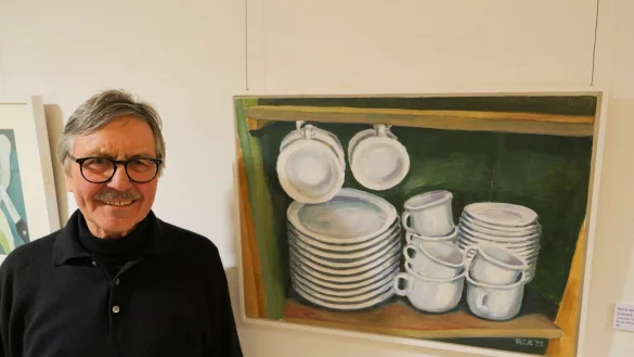 Vernissage der Ausstellug "Zwei Brüder": Joachim Tatje steht vor seinem Bild "Nicht alle Tassen im Schrank" aus dem Jahr 2022. - © Thomas Krügler