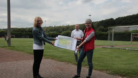 Auf dem Sportplatz in Langenholzhausen pr&auml;sentieren Ute Seidemann (links) und Cornelia Rehse zusammen mit B&uuml;germeister Mario Hecker die Pl&auml;ne f&uuml;r den Umbau - falls die F&ouml;rdermittel kommen.&nbsp; - &copy; Carolin Brokmann-F&ouml;rster