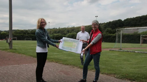Auf dem Sportplatz in Langenholzhausen pr&auml;sentieren Ute Seidemann (links) und Cornelia Rehse zusammen mit B&uuml;germeister Mario Hecker die Pl&auml;ne f&uuml;r den Umbau - falls die F&ouml;rdermittel kommen. - &copy; Carolin Brokmann-F&ouml;rster