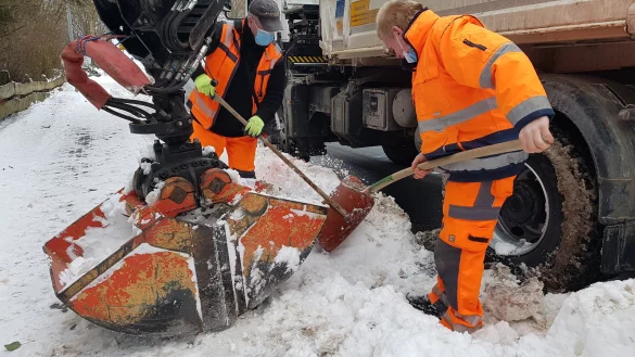Jetzt m&uuml;ssen die Gullideckel befreit werden: Christian Glata (links) und David Oppermann legen vor allem an den neuralgischen Stellen Hand an, hier in H&ouml;he der Julius-M&uuml;ller-Stra&szlig;e in Schwalenberg. Denn sobald es taut, wird hier das Wasser auf der Stra&szlig;e stehen, wissen die Mitarbeiter des st&auml;dtischen Bauhofs. - &copy; Marianne Schwarzer