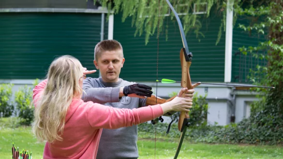 Trainerin Marina Laukert erklärt Dimitri Iljuschin im Bad Meinberger Kurpark die wichtigsten Regeln des Bogenschießens. - © Raphael Bartling