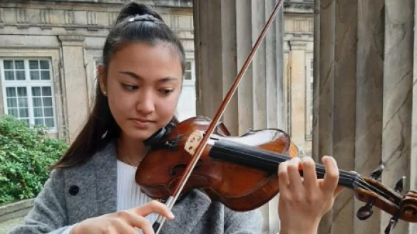 In ihrem Element: Gina Keiko Friesicke steht mit ihrer Geige vor der Musikhochschule in Detmold und entlockt ihrem Instument einige T&ouml;ne.&nbsp; - &copy; Julia Kube