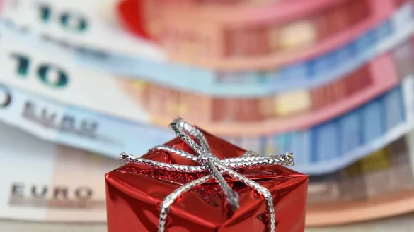 Ein rotes Geschenkpaket mit einer silbernen Schleife liegt auf Geldscheinen. - &copy; Jens Kalaene/dpa-Zentralbild/dpa