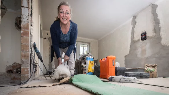 Sch&ouml;ne &Uuml;berraschung: Unter dem grasgr&uuml;nen Teppichboden im Wohnzimmer hat Bauherrin Helga Gerster wundersch&ouml;nes Fischgr&auml;t-Eichenparkett gefunden. Immer interessiert mit dabei: ihre H&uuml;ndin Lilli. - &copy; Mike-Dennis Mueller