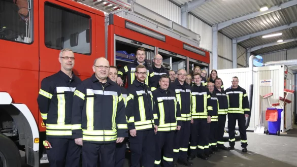 Ein Gro&szlig;teil der rund 25 Feuerwehrfrauen und -m&auml;nner steht an dem Fahrzeug, mit dem sie im Notfall von Asemissen aus ausr&uuml;cken. Hinten rechts sind die Container zu sehen, in denen Umkleiden und Toiletten untergebracht sind. - &copy; Birgit Guhlke
