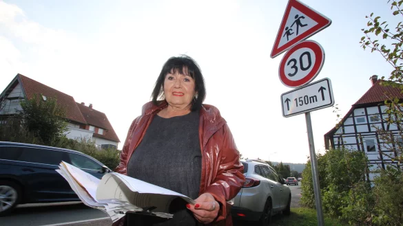 Daisy Krüger steht vor dem fraglichen 30er-Schild in der Ortsdurchfahrt Erder. Hier oder - nach Darstellung des Kreises - deutlich weiter die Straße hinunter wurde sie geblitzt. In der Hand hält die Kalldorferin den Aktenordner mit ihren Unterlagen zu dem Fall. - © Jens Rademacher