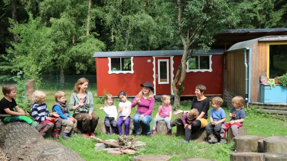 So sieht der Normalfall aus: Waldkindergartenleiterin Jelka Malin Karger (Mitte) und die Erzieherinnen Anke Sj&ouml;berg (links) und Lara Trojak singen mit den Kindern im Morgenkreis. Im Hintergrund ist der Bauwagen zu sehen. - &copy; Carolin Brokmann