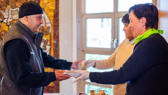 Timucin Sirin (links) nimmt einen Teller Gulaschsuppe von Judith Brazier (rechts) entgegen. Maria Tuschewitzki reicht ein Stück Brot. - © Raphael Bartling