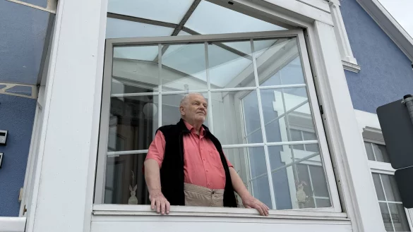 Der frühere Bundestagsabgeordnete Hans Verheyen im Windfang seines Hauses: Die riesigen Lüftungsanlagen auf dem Dach des benachbarten Lidl-Marktes an der Teutoburger Straße machen so viel Lärm, dass es durchs geschlossene Fenster zu hören ist, klagt er. - © Martin Krause