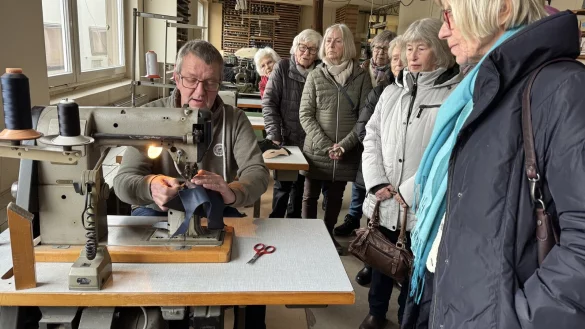 Klaus S&uuml;llwald demonstrierte in seinem Museum die Schritte der Schuhherstellung an der N&auml;hmaschine, w&auml;hrend die Damen-Boule-Gruppe aus W&uuml;lfer-Bexten gespannt zuschaut. - &copy; Sandra Castrup
