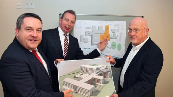 Perspektiven für das Klinikum: Dr. Axel Lehmann, Dr. Johannes Hütte und Dr. Helmut Middeke (von links) zeigen die Ausbaupläne für den Standort Detmold. Die orangen Erweiterungen auf dem Grundriss liegen auf dem Luftbild vorn. Der neue OP-Bereich dockt an den Querriegel an, auf der vorderen Projektskizze ist er auf der linken Seite als graues Quadrat zu sehen. - © Bernhard Preuss