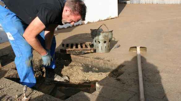 Aufr&auml;umarbeiten: Mark J&auml;ger gr&auml;bt einen Kanal frei, der durch den Matsch verstopft ist. Sein ganzer Hof, der an Werkstatt und Tankstelle an der Extertalstra&szlig;e grenzt, war vollgelaufen. - &copy; Kirsten Fuhrmann