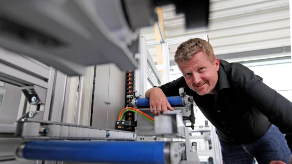 Prof. Oliver Niggemann vom Fraunhofer Institut zeigt das Modell eines Hochregals, das selbstst&auml;ndig den k&uuml;rzesten Weg sucht und seinen Energieverbrauch reguliert. - &copy; Foto: Vera Gerstendorf-Welle