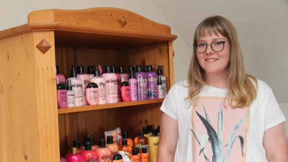 Lisa Ritter vor einem Teil ihrer bunten Duschgel-Sammlung, die farblich sortiert und somit dekorativ im Wohnzimmerschrank ihren Platz gefunden hat. - &copy; Nadine Uphoff