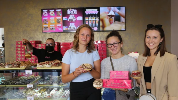 Die Sch&uuml;lerinnen Leonie Rief, Regina Daniels und Leticia Adamczyk (vlnr) lassen sich gern mit den kunstvollen Kreationen des "Royal Donut" fotografieren. Mitinhaber Abbas Kahil kann ihnen dazu allein heute mehr als 25 bunte Sorten anbieten - &copy; Alina Hetland