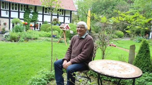 Ulrich K&auml;thner sitzt in seinem Garten - zwar nicht unter Kastanienbaum "Michel", aber der Platz gef&auml;llt ihm mindestens genauso gut. Im Hintergrund ist das unter Denkmalschutz gestellte Fachwerkhaus zu sehen, das vor 30 Jahren saniert wurde. Der G&auml;rtner mags naturbelassen. - &copy; Kirsten Fuhrmann