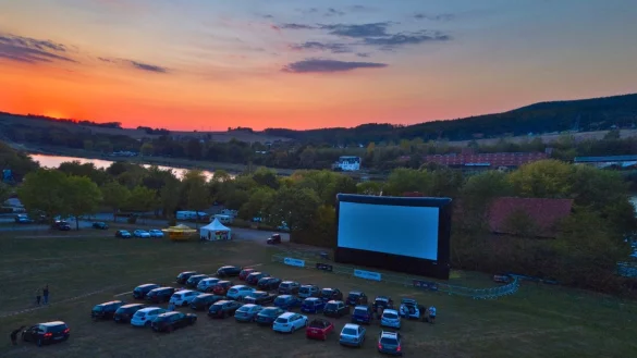 Autokino: Die Fahrzeuge nehmen lange vor Filmbeginn Aufstellung vor der gro&szlig;en Leinwand auf dem Parkplatz, w&auml;hrend die Sonne &uuml;ber dem Schiedersee romantisch untergeht. - &copy; Wolfgang Furmanski
