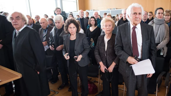 Die Zeugen der Nebenklage, William Glied (r-l), Irene Weiss, deren Tochter, Max Eisen und Mordechai Eldar sowie ihr Anwalt Thomas Walther (l) stehen am 19.02.2016 in Detmold (Nordrhein-Westfalen) beim Einzug des Gerichts an ihren Plätzen. Dem 94-Jährigen ehemaligen SS-Wachmann Hanning wird Beihilfe zum Mord in mindestens 170000 Fällen vorgeworfen. Der Prozess vor dem Landgericht Detmold findet in den Räumen der Industrie und Handelskammer statt. - © dpa