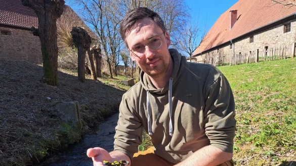 Fabian Fester hält ein Modell eines Feuersalamanders in Händen. Hier im Garten der Biologischen Station gibt es die Amphibien zwar nicht, Bachläufe aber brauchen sie. - © Carolin Brokmann-Förster