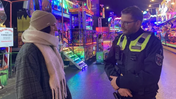 Sebastian Sch&ouml;ps vom Kommunalen Ordnungsdienst unterh&auml;lt sich mit Andreasmesse-Besucherin Karina Kirst auf dem Kronenplatz. - &copy; Cordula Gr&ouml;ne