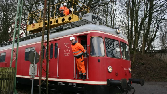 Raphael Kahlert (vorn) sowie Adrian Fahrenkamp und Frank Muth (oben) arbeiten vom Turmtriebwagen aus an der Oberleitung. Dort stehen ein neuer und ein alter Mast noch nebeneinander. - &copy; Sylvia Frevert