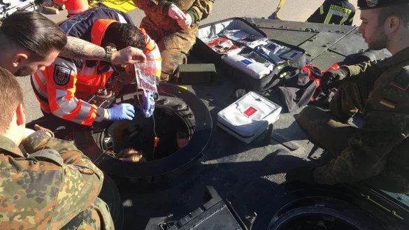 Hilfe kommt durch die Luke: Der Rettungsdienst versorgt den Soldaten, während die Feuerwehr im Innern des Panzers die Stange kappt, die seinen Steifel durchbohrt hat. - © Freiwillige Feuerwehr Augustdorf