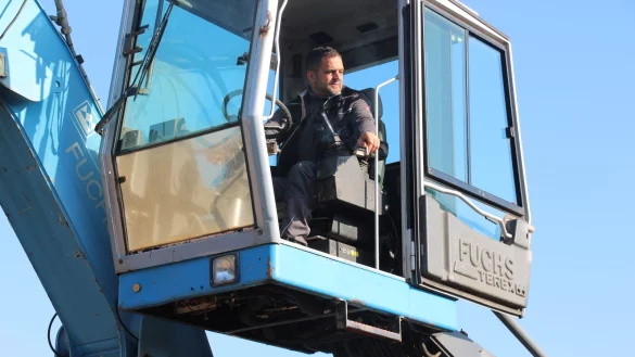 Der Chef legt selbst Hand im Bagger an. Seine beiden Mitarbeiter stehen w&auml;hrenddessen unten und sortieren Kleinteile vor. - &copy; Janet K&ouml;nig