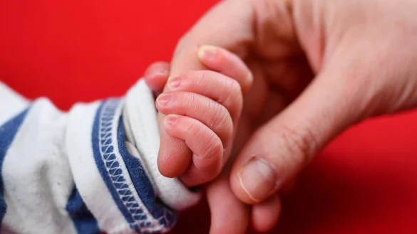 Mutter und Neugeborenes halten H&auml;nde - &copy; Foto: Uwe Anspach/dpa-tmn