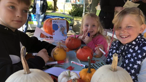  Im Bild bemalen die Geschwister Luke (9), Lara (3) und Lucy (5, von links) Kürbisse am Stand der Volkshochschule. - © Thomas Reineke