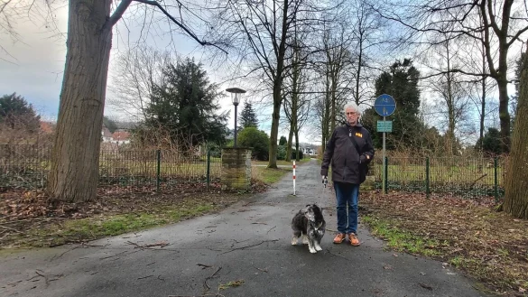 Seniorenbeauftragter Werner Wahlers mit Juno vor dem Radweg, der über den Friedhof Rintelner Straße führt. Diese direkte Querung hinüber zur Straße Hinter den Friedhöfen ist erlaubt, nicht aber auf den anderen Wegen. - © Katrin Kantelberg