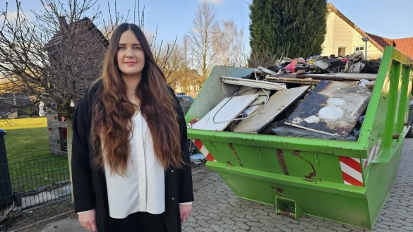 Susanne Semler hilft einer Familie, die bei einem Brand alles verloren hat. Das Haus im Sandkamp wird derzeit ausgeräumt, in der Mulde liegen die verbrannten und zerstörten Sachen. - © Astrid Sewing