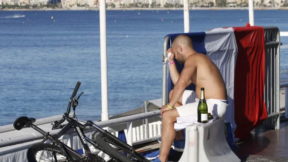 Verzweifelt sitzt ein Mann am Morgen nach dem Attentat nahe des Tatorts auf einer Absperrung. Die Champagnerflasche zeigt, dass hier gerade noch gefeiert wurde. - &copy; Reuters