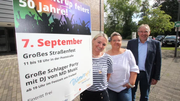 Planen das Programm f&uuml;r &bdquo;50 Jahre D&ouml;rentrup": (von links) Antje Schake und Anke Kluckhuhn als Organisatorinnen von der Gemeindeverwaltung sowie B&uuml;rgermeister Friedrich Ehlert stehen vor dem Rathaus neben einem Plakat zum Jubil&auml;um. - &copy; Jens Rademacher