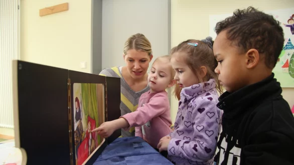Fachkraft Meike Koch erz&auml;hlt (von links) Milena, Joleen und Hadiyatou die Geschichte von Dornr&ouml;schen am Kamishibai, einem japanischen Erz&auml;hltheater. - &copy; Jana Beckmann