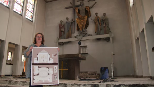 Christiane Berghahn zeigt den Plan nach dem der Chorraum verändert werden soll. Erkennbar sind die reduzierte Rückwand und die bogenförmige Gestaltung der Stufen. - © Dieter Asbrock