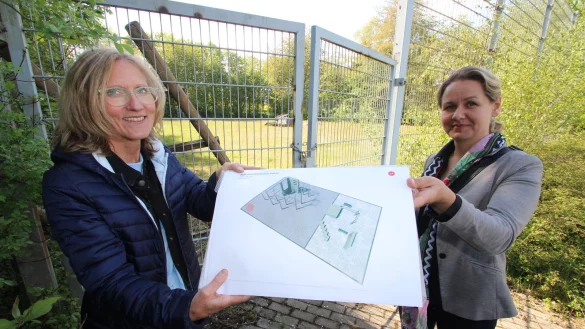 Ute Seidemann (links) und Ewa Hermann vom Bauamt der Gemeinde Kalletal stehen vor dem zurzeit verschlossenen ehemaligen Basketballplatz und zeigen den Plan f&uuml;r die Parkour-Anlage. - &copy; Jens Rademacher