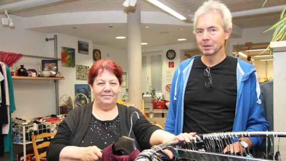 Mitarbeiterin Frieda Ivanova hängt eine Jacke an ihren Platz in der AWO-Boutique. Rüdiger Detering ist Leiter des Beschäftigungsprojektes. - © Nadine Uphoff