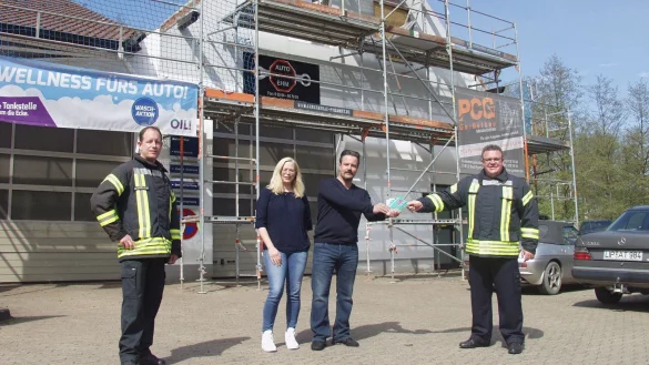 &Uuml;bergabe der Tankgutscheine vor der Brandstelle &uuml;ber der Werkstatt: L&ouml;schzugf&uuml;hrer Marcus Hermann, Merle und Holger Ehm sowie Gemeindebrandinspektor Michael Gr&uuml;ttemeier (von links). - &copy; Wulf Daneyko