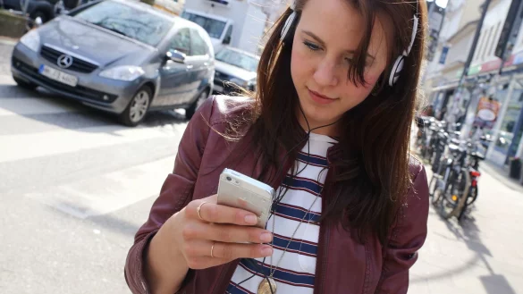 Ein weiblicher Smombie mit Kopfh&ouml;rer. Der Blick aufs Handy, die Ohren mit Musik beschallt. So ist man im Stra&szlig;enverkehr besonders in Gefahr. - &copy; Symbolfoto: picture alliance / dpa
