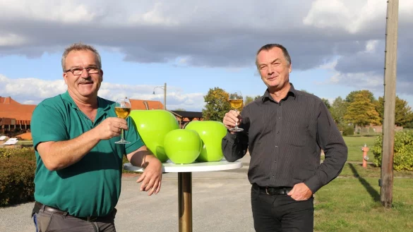 LWL-Ziegeleimuseums Gesch&auml;ftsf&uuml;hrer Willi Kuhlke (rechts) und Garten und Landschaftsbauer Frank Wilhelmi (links) sto&szlig;en mit einem Apfelsaft auf das kommende "Himmel und Erde"- Fest an: Beide werden in der Jury zur Wahl des "Besten Lippischen Apfelsaftes" sitzen, f&uuml;r den die gl&auml;nzenden Pokale in Apfelform (Mitte) vorgesehen sind. - &copy; Alina Hetland