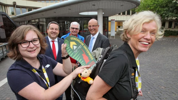 Startbereit: Landesverbandsvorsteherin Anke Peithmann hat ihren Rucksack gepackt und aufgeschnallt, Silvia Röllvon der Deutschen Wanderjugend versorgt das mitreisende Maskottchen noch mit dem offiziellen Logo des 118. Deutschen Wandertages. Im Hintergrund (von links) sehen Lippes Landrat Dr. Axel Lehmann, Rüdiger Schmidt vom Teutoburger-Wald-Verein und Detmolds Bürgermeister Rainer Heller zu. - © Bernard Preuss