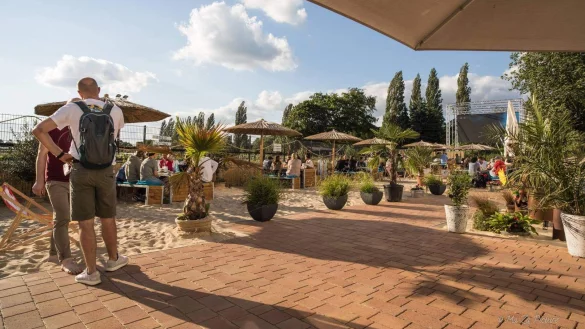 Der &bdquo;Salina Beach" an der Diskothek &bdquo;Glashaus" am Begakamp. Die G&auml;ste sitzen auf Strandb&auml;nken im Sand. Rechts im Hintergrund ist die gro&szlig;e LED-Wand zu sehen.&nbsp; - &copy; Glashaus