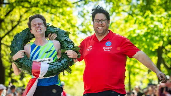 Schon beim Zieleinlauf fließen bei Florian Bochert die Tränen. Orgateam-Leiter Daniel Skakavac freut sich, seinem Vereinskollegen den Kranz überwerfen zu dürfen. - © Sarah Jonek