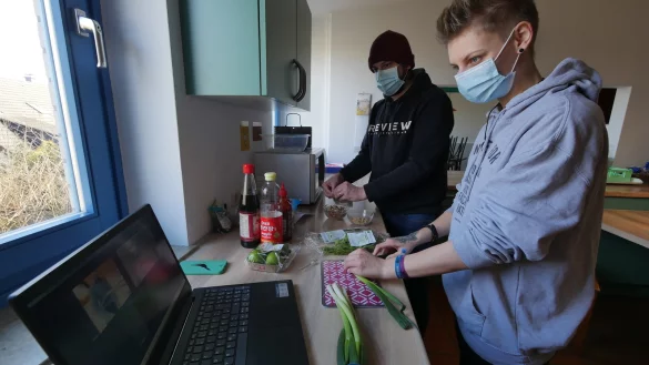 Sozialarbeiter Anne Brouwer (vorne) und Pascal Schien kochen mit Hilfe einer Zoom-Videokonferenz gemeinsam mit Jugendlichen. - &copy; Jost Wolf