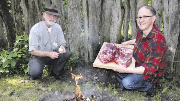 Feuriger Auftakt: Einige Basaltsteine werden durch Harry Meyer (links) und Karl Banghard in einem Holzfeuer erhitzt. Auf den gl&uuml;henden Steinen br&auml;t das Fleisch und das Gem&uuml;se dann unter der Erde. - &copy; Horst Biere