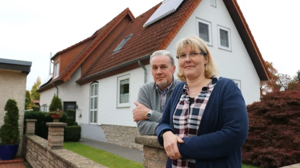 Anja und Frank Hanfmann vor ihrem sanierten Heim. Der vordere Teil des Hauses ist bereits 1937 gebaut worden und wurde gedämmt. Auf dem Dach wurden eine Photovoltaik- und eine Solarthermie-Anlage installiert. - © Till Sadlowski