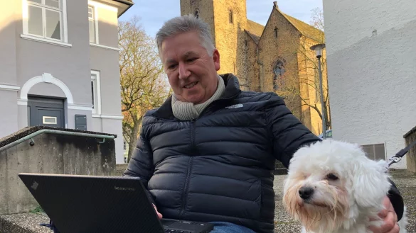 Dr. Johann Malcher sitzt mit Familienhund &bdquo;Dusty" auf der Treppe zum Sch&ouml;tmaraner Kirchplatz. - &copy; Sven Kienscherf