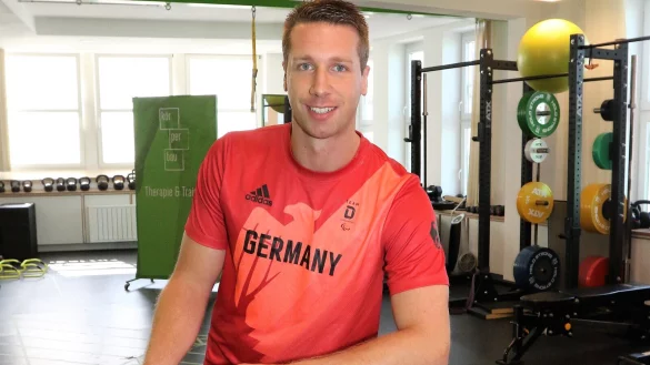 Raphael Rochner pr&auml;sentiert stolz ein Shirt der Para-Rad-Nationalmannschaft, das in den R&auml;umen seiner Physiotherapie aufgeh&auml;ngt ist. - &copy; Oliver K&ouml;nig
