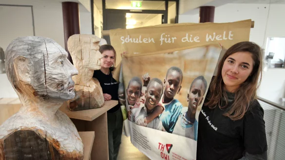 Lara Nelli&szlig;en (rechts) und Tabea Pape halten das Banner. Die Holzk&ouml;pfe und viele weitere Kunstwerke werden bei der Auktion versteigert. - &copy; Bernhard Preu&szlig;